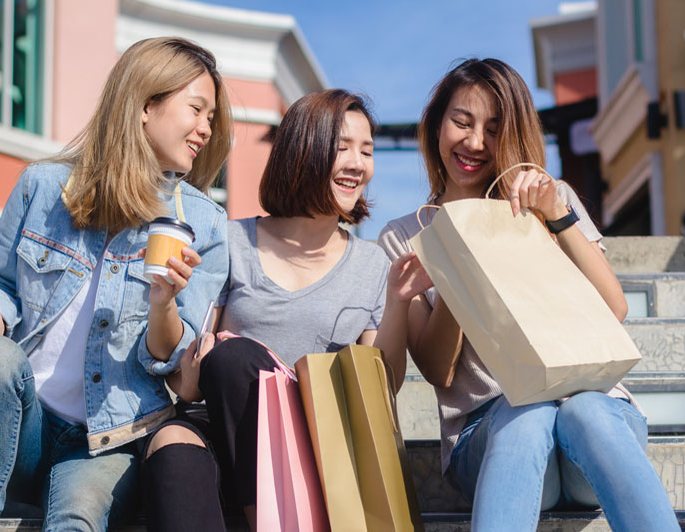 Friends sitting on steps with shopping bags
